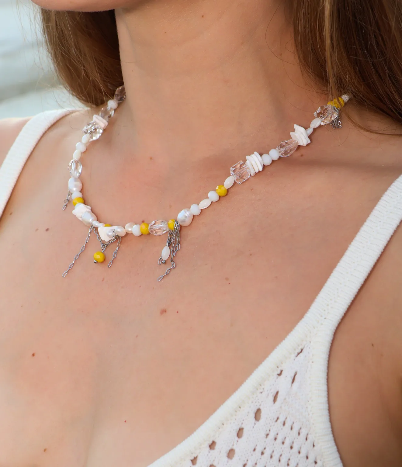 Sunny yellow accents, white details and fine moving chains bring light and playful movement to this necklace.