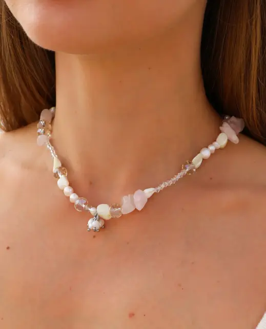 A romantic necklace in blush pink and creamy white, with clear facets and a small dangling cluster.