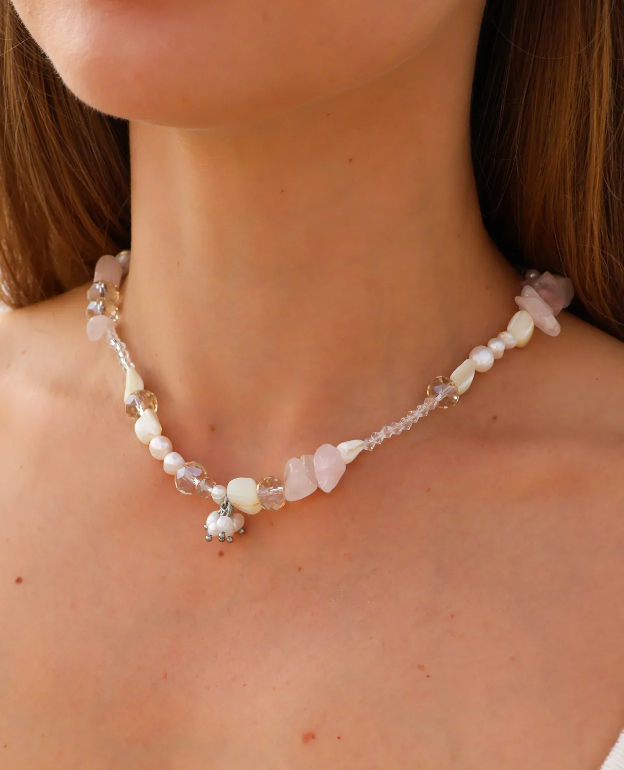 A romantic necklace in blush pink and creamy white, with clear facets and a small dangling cluster.