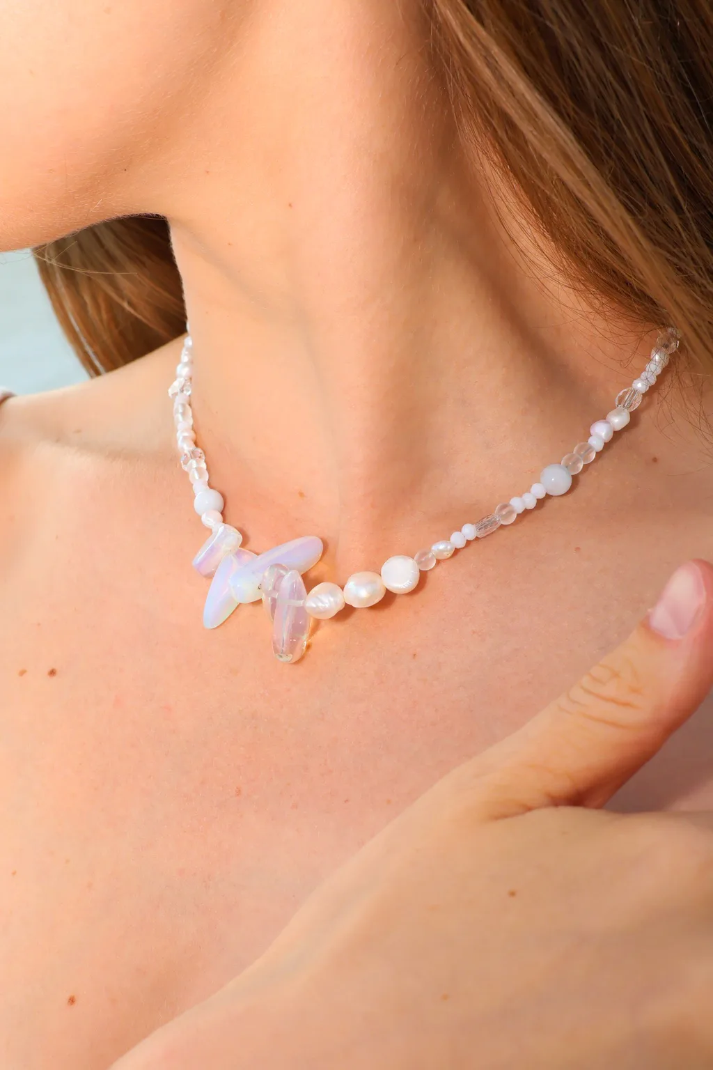 Luminous white tones and sculptural iridescent accents create a delicate necklace with an unexpected silhouette.