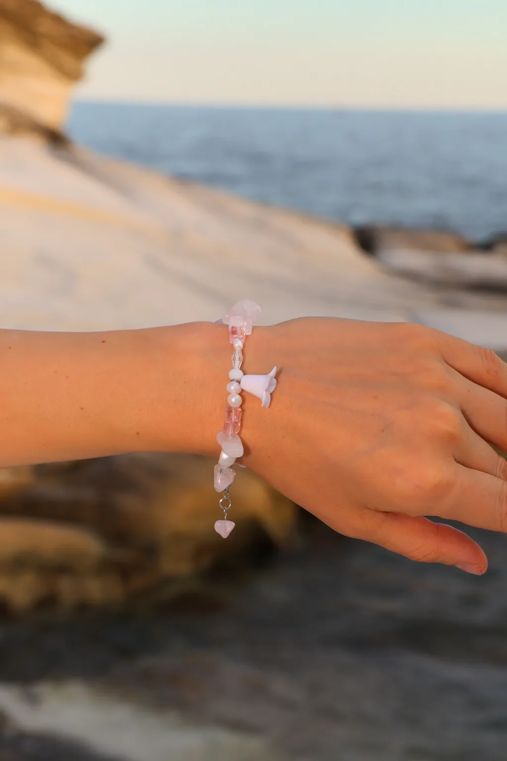 A delicate bracelet with blush-pink accents, clear details and a little flower pendant.