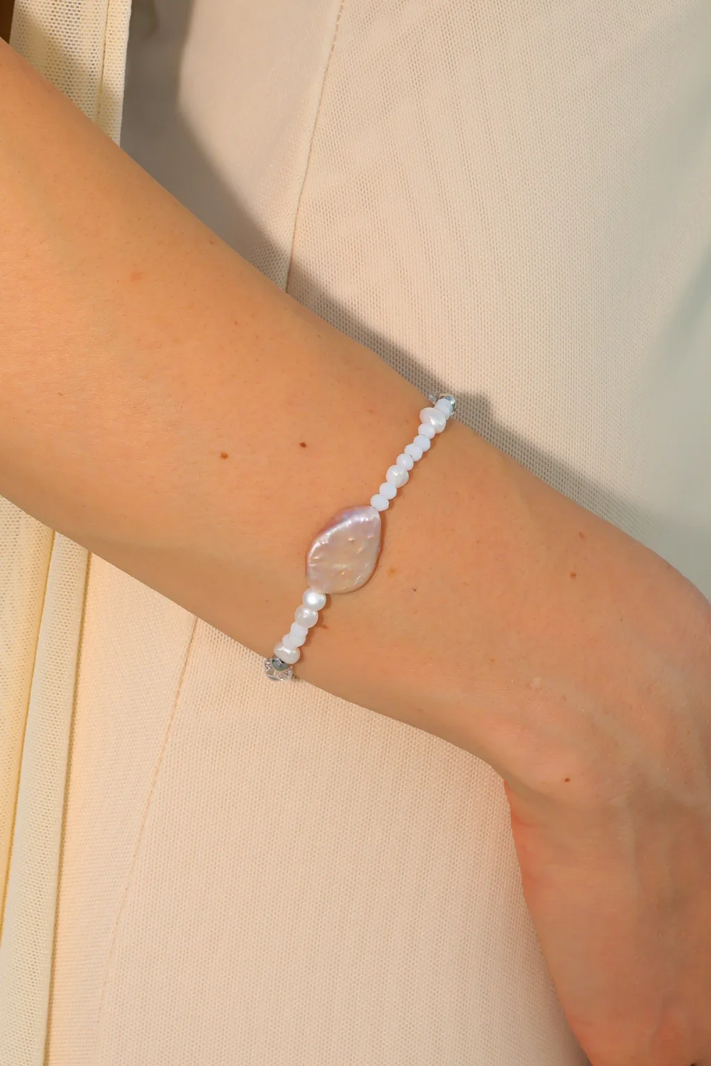 A luminous central pearl and delicate white details create a quiet, elegant accent for every day.