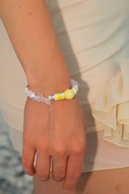 Sunny yellow accents, blush-pink details and floral beads bring a little summer garden to your wrist.