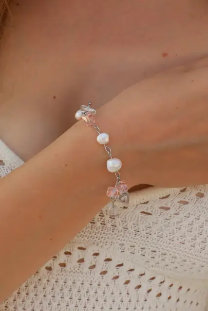 Rosé Charm bracelet with freshwater pearls and pink dangling details on a wrist